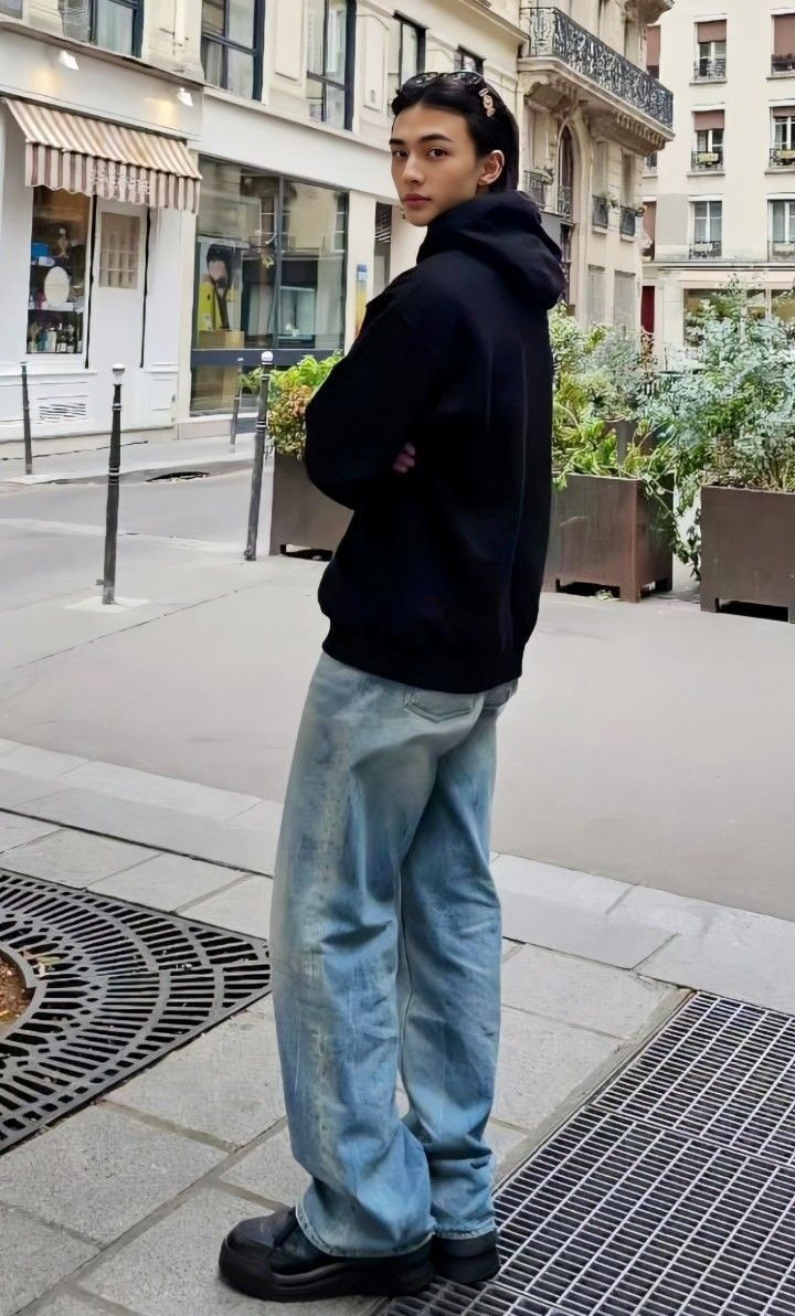 a young man is standing on the sidewalk