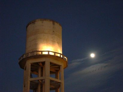 an old water tower with the moon in the background