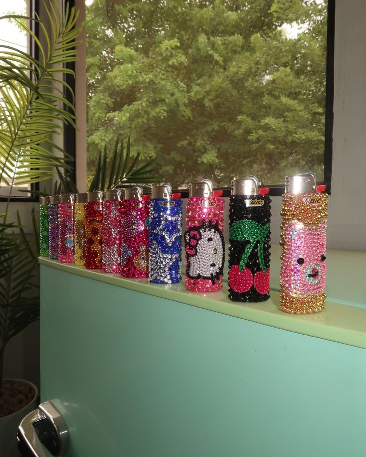 a row of colorful flasks sitting on top of a window sill next to a potted plant