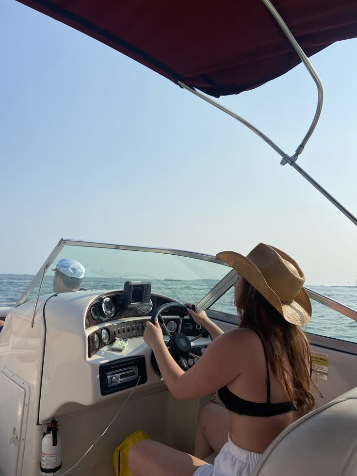 a woman in a hat is driving a boat