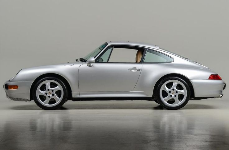 a silver sports car parked on top of a cement floor next to a white wall