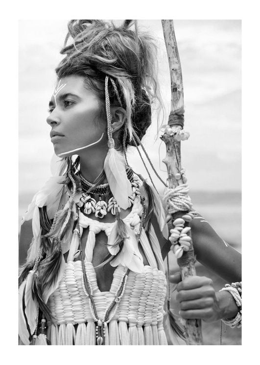 a woman in native clothing holding a stick