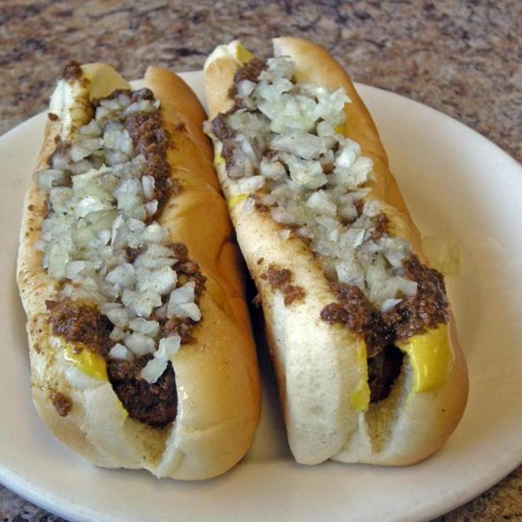 two hot dogs with onions and mustard on a plate