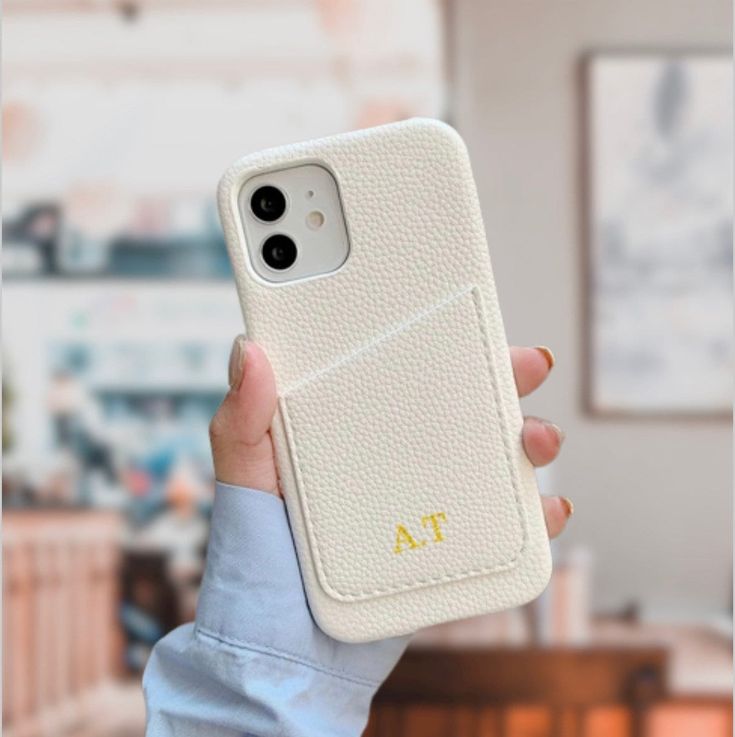 a person holding up a phone case with the initials on it