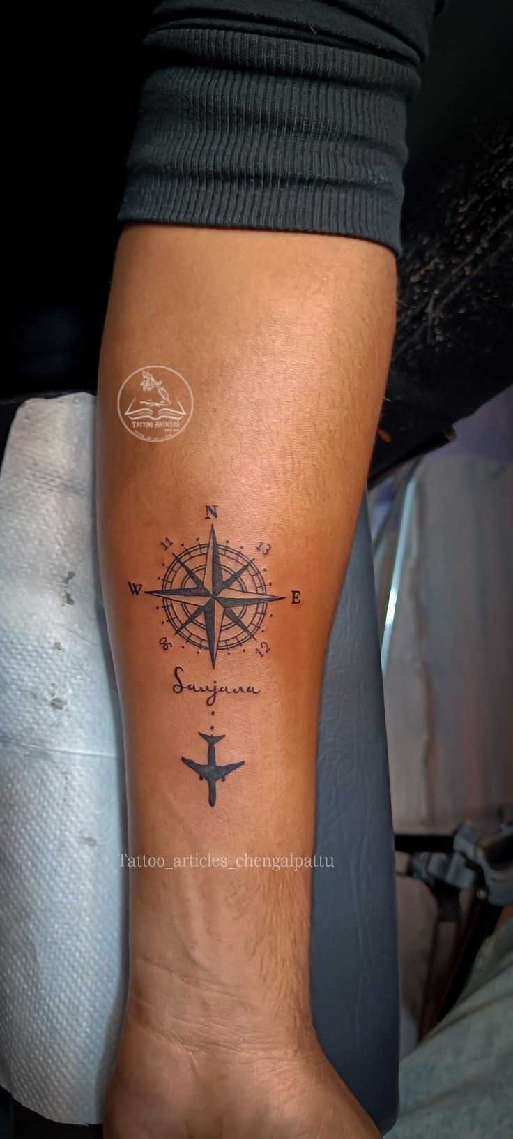 a person with a compass tattoo on their arm and leg, while the other hand is holding