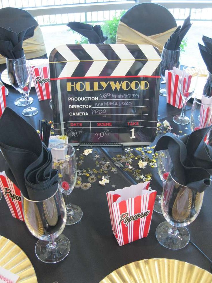 a movie themed party with popcorn, wine glasses and black napkins on the table