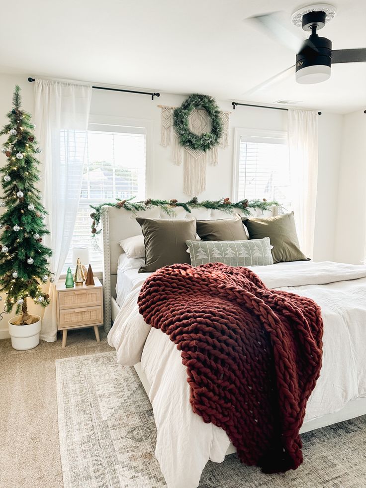 a bedroom decorated for christmas with wreaths on the window sill and bedding