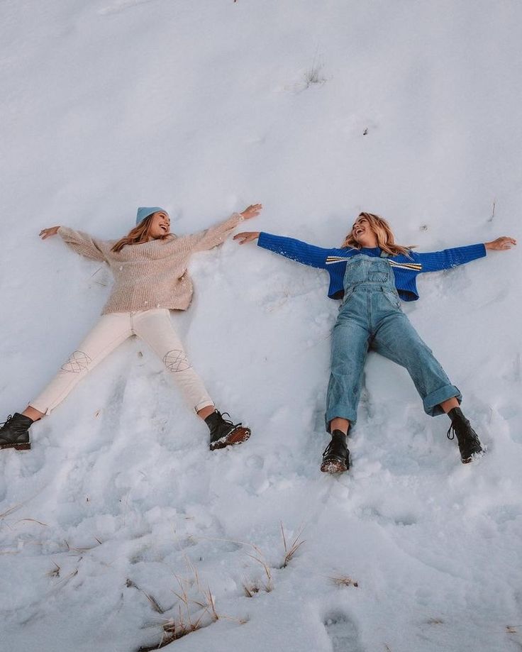 two women laying in the snow with their arms outstretched