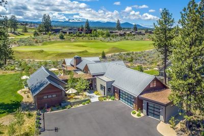 an aerial view of a home in the mountains with golf course and trees around it