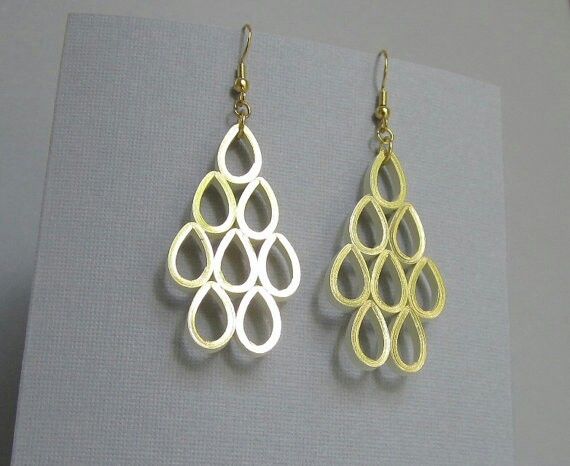 two pairs of gold and silver earrings on top of a gray surface with a white background