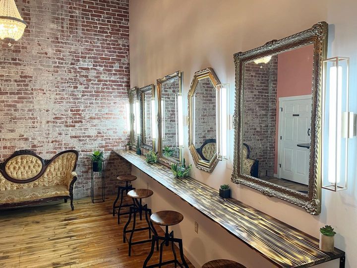 a row of mirrors sitting on the side of a brick wall next to stools