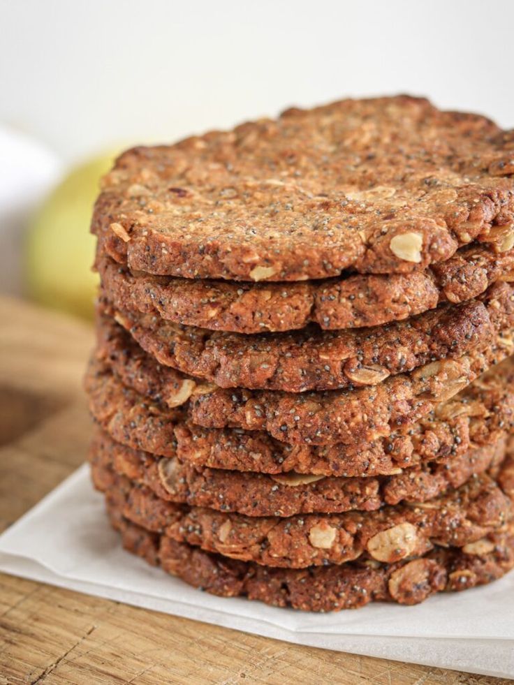 a stack of cookies sitting on top of a wooden cutting board next to an apple