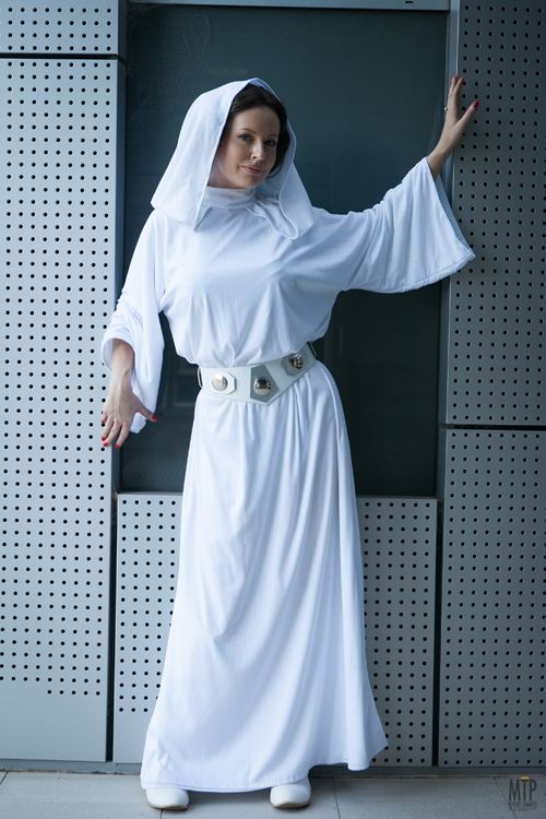 a woman dressed in white is standing against a wall with her hands out and arms outstretched