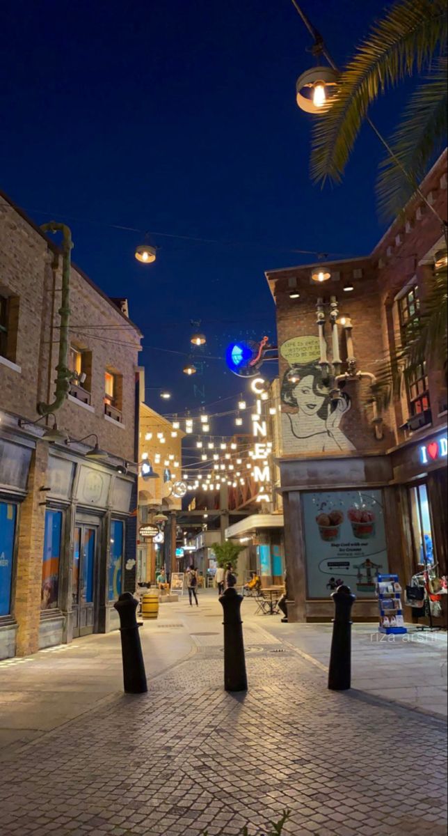 an empty city street at night with lights hanging overhead