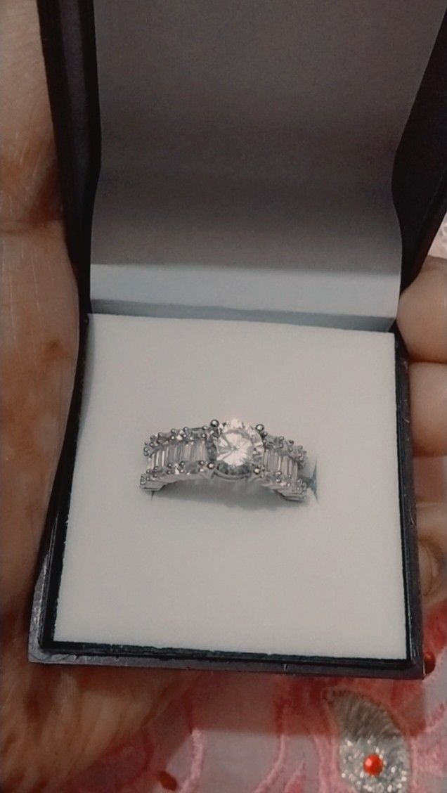 a woman's hand holding an engagement ring in a box