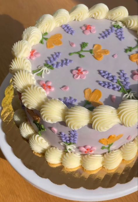 a cake with white frosting and colorful flowers on it sitting on a wooden table