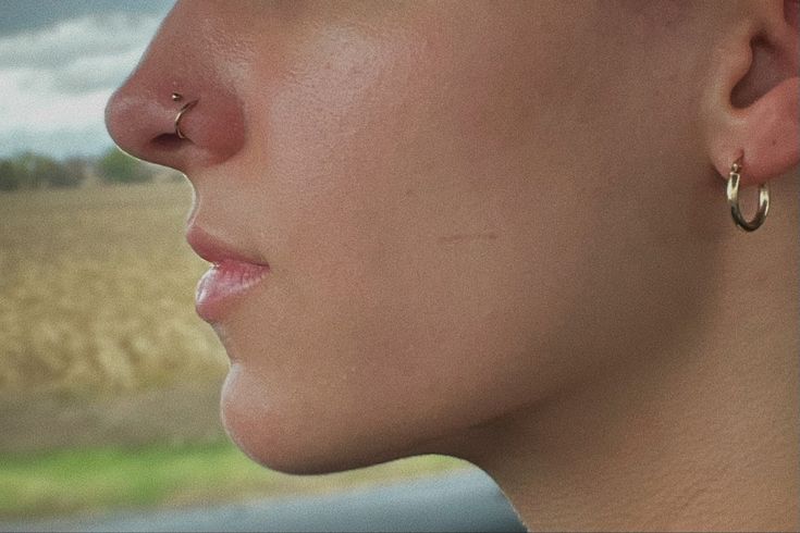 a close up of a woman's face with ear piercings on her nose