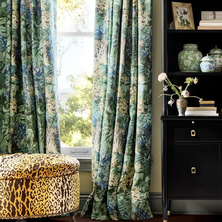 a living room with a leopard print foot stool and curtains in front of a window