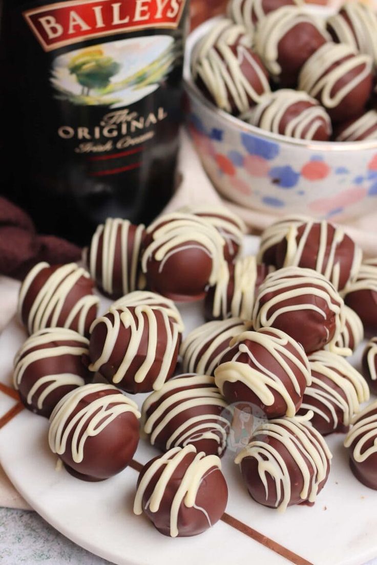 chocolate covered candies on a plate with a bottle of bailey's in the background