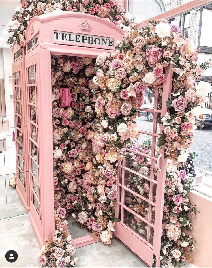 a pink phone booth covered in flowers