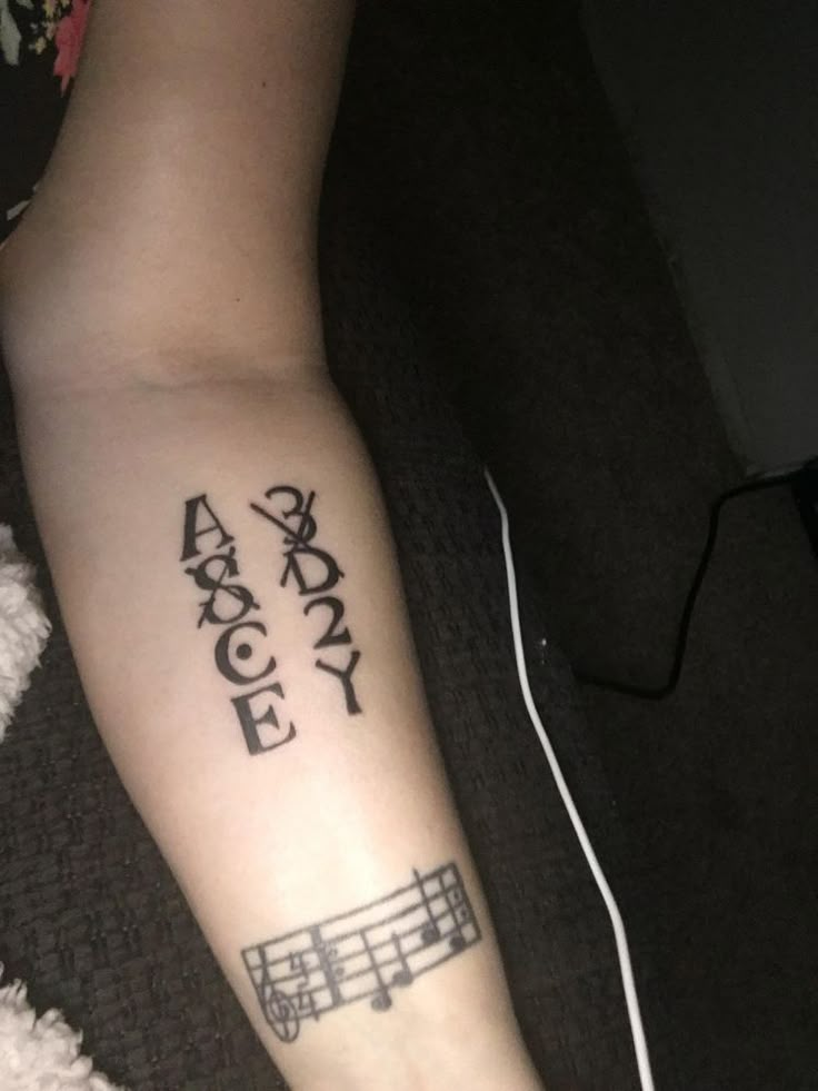 a person with a tattoo on their arm that reads, and an image of musical notes