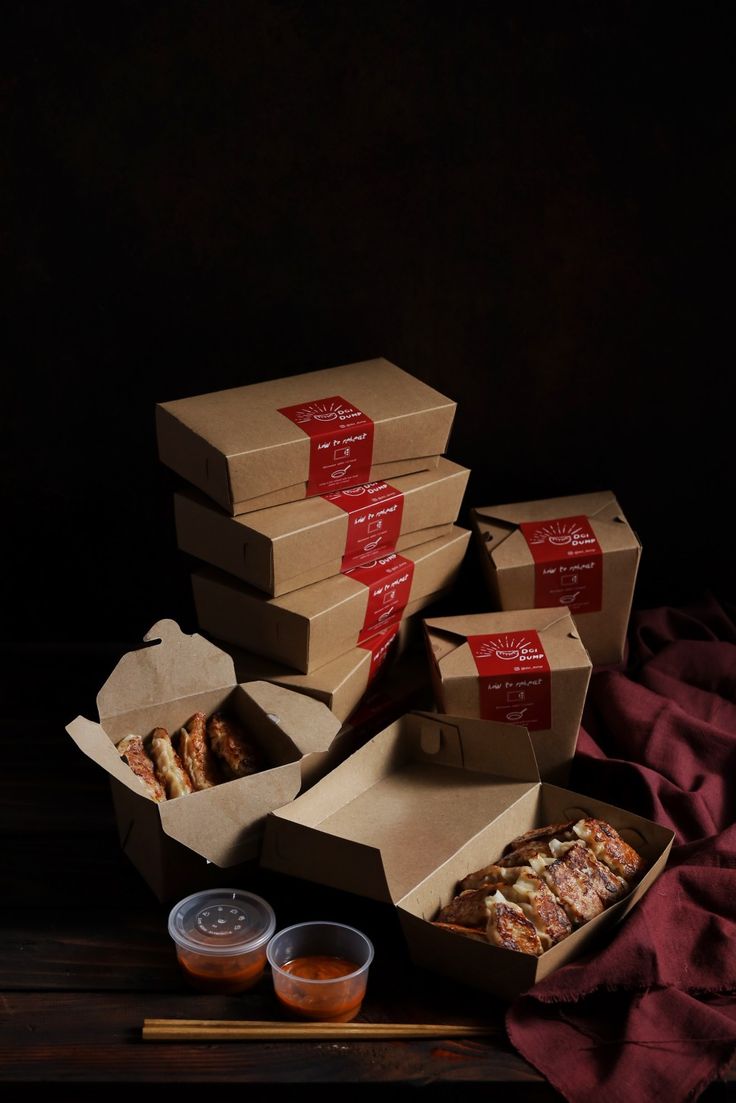 several boxes of pizza sitting on top of a table next to some chopsticks