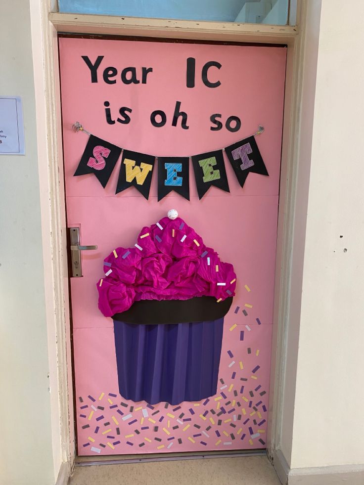 a pink door decorated with a cupcake and streamers for a new year's celebration