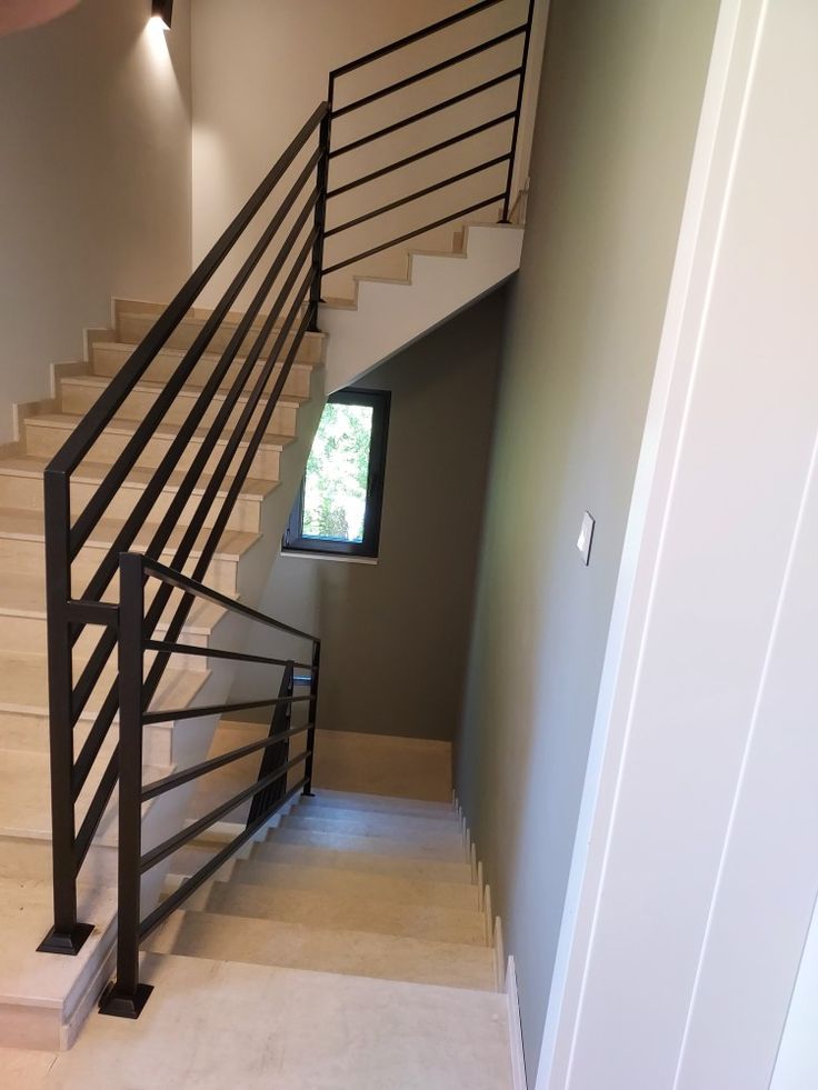 a stair case in the corner of a room with a window on one side and an open door on the other