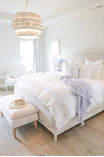 a white bedroom with a large bed and foot stool