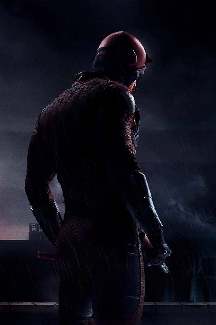 a man standing in the rain wearing a red helmet