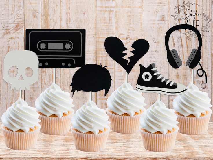 there are cupcakes that have been decorated with white frosting and black decorations