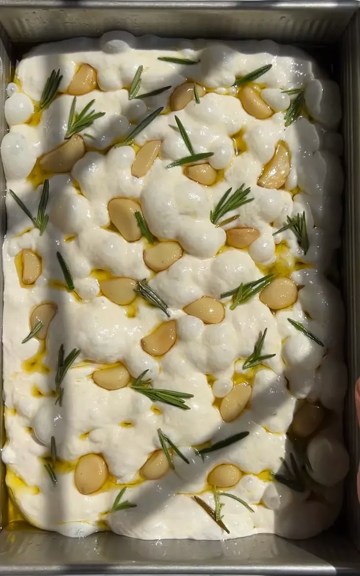 a pan filled with food sitting on top of a table next to a person's hand