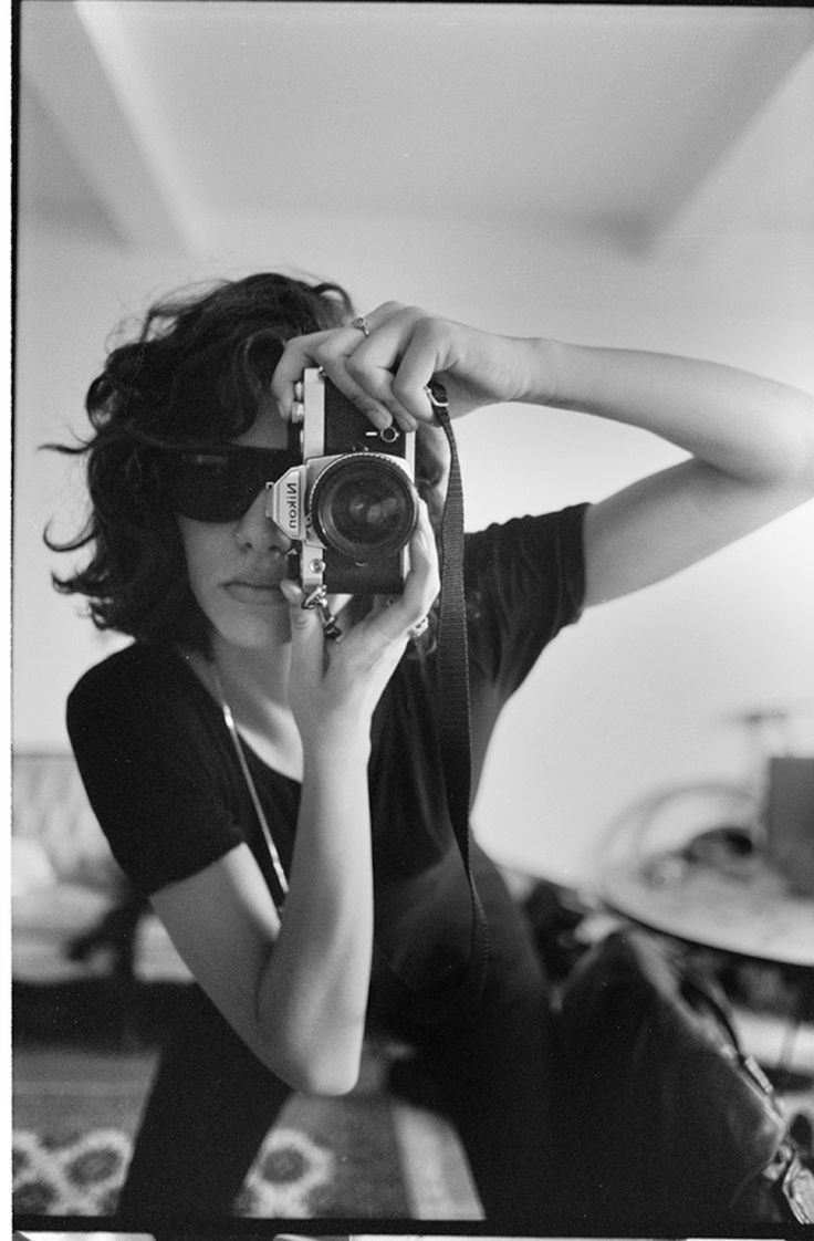 black and white photograph of a woman holding up a camera