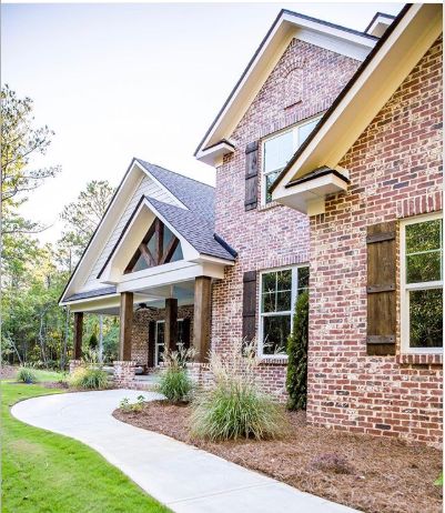 a brick house with green grass and trees