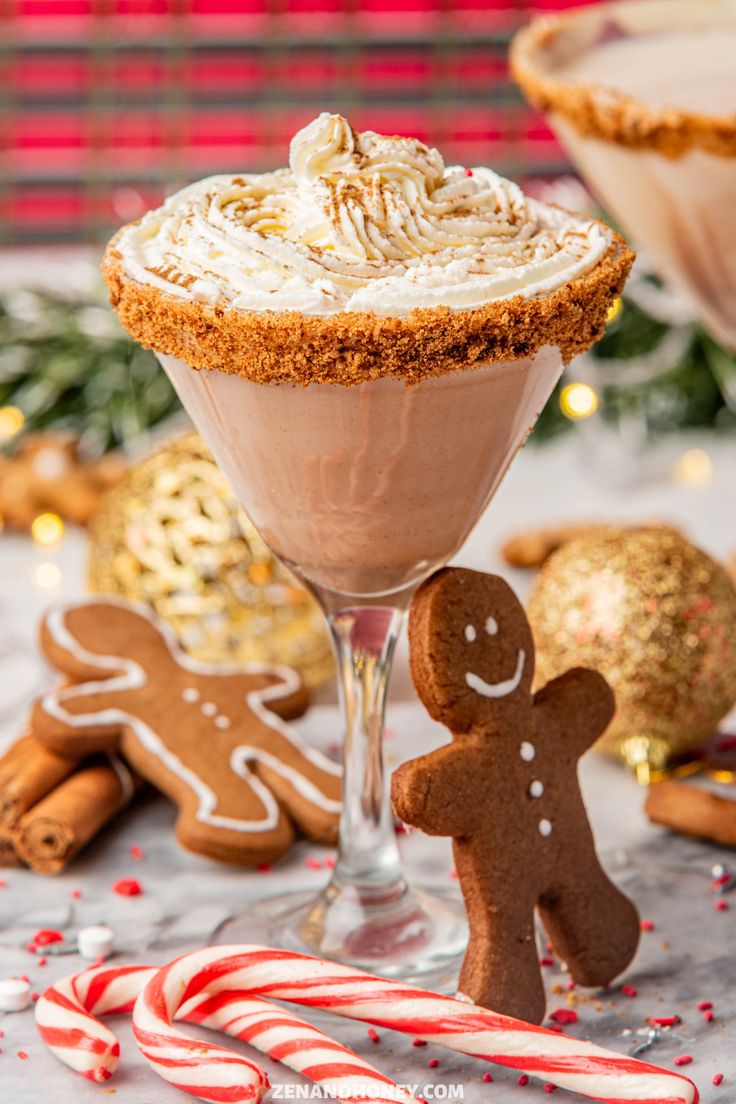 a dessert in a glass next to some candy canes and gingerbread cookies on a table