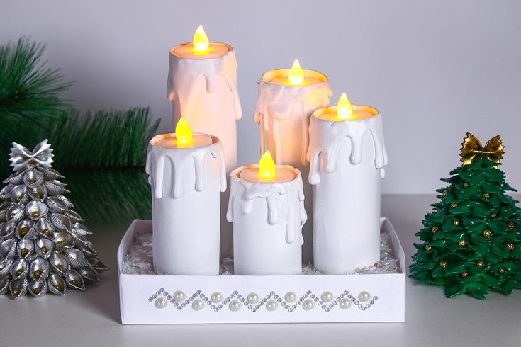 some candles are sitting on a tray next to a small christmas tree and pine trees