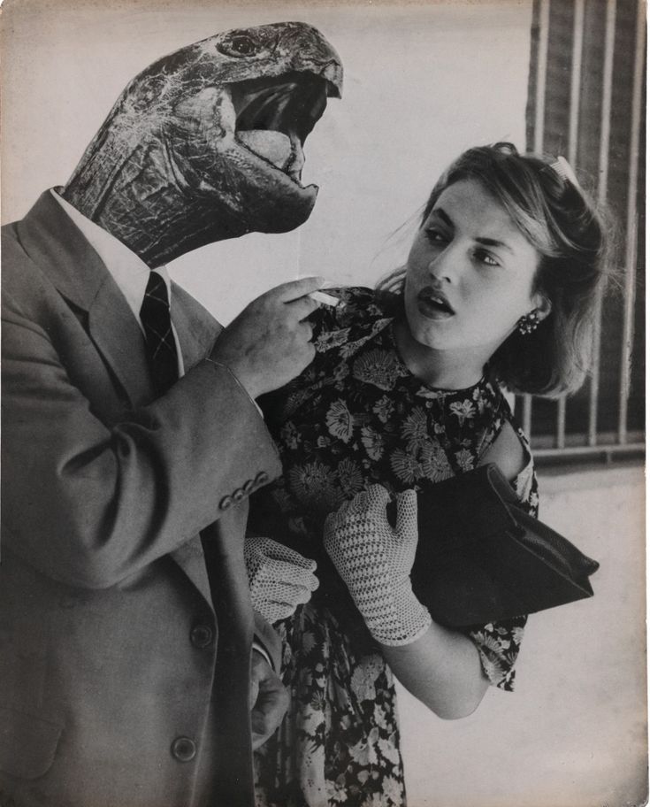 an old photo of a woman holding a man in front of a large dinosaur head