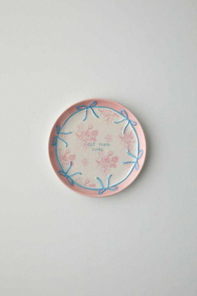 a pink and blue plate sitting on top of a white table next to a wall