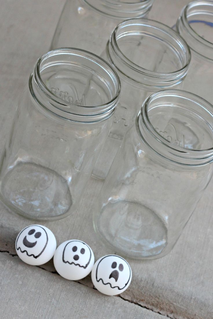 four mason jars with faces painted on them sitting next to each other in front of some empty glass jars