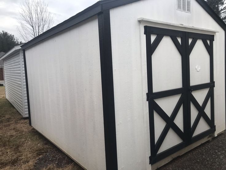 a white and black shed sitting on top of a grass covered field