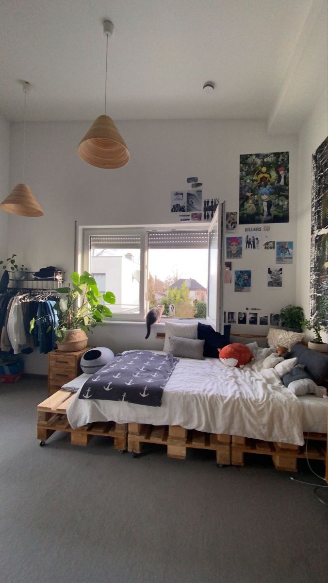 a bed made out of wooden pallets in a room with plants and pictures on the wall