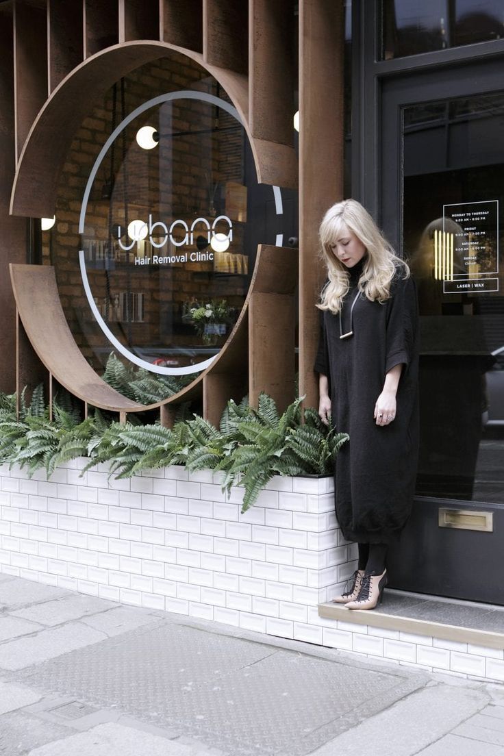 a woman standing in front of a building with a large circular mirror on the wall