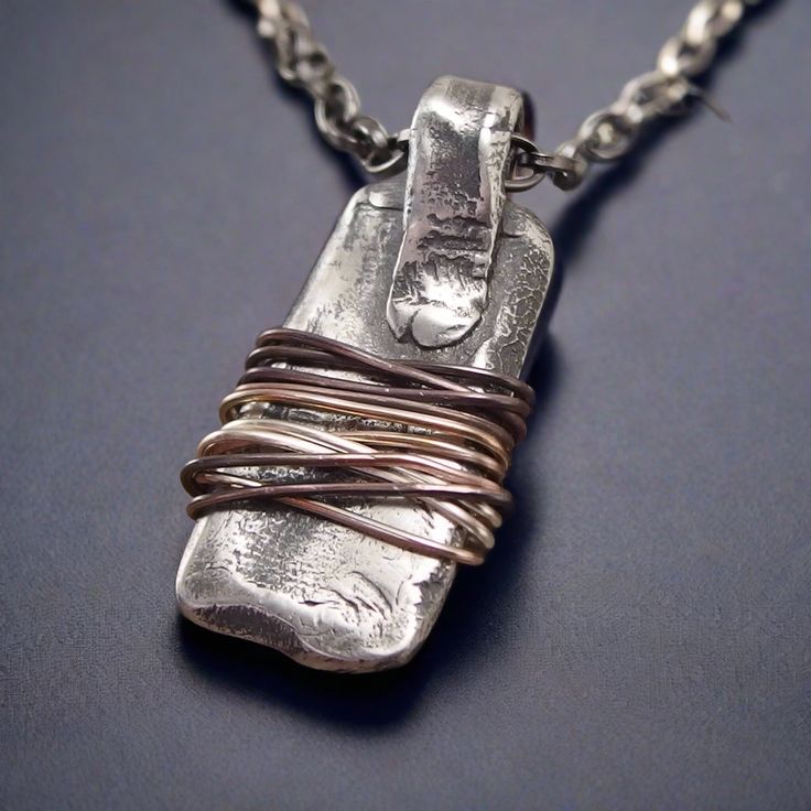 a necklace made out of silver wire with a bottle in the middle on a chain