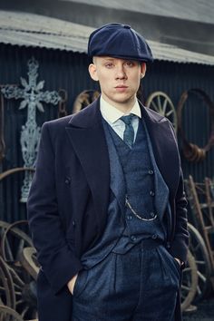 a man in a suit and hat standing next to a building