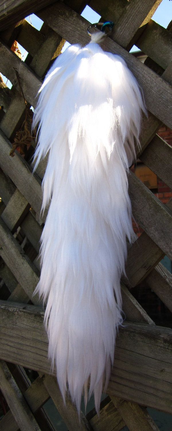 a white feather is hanging on a wooden fence