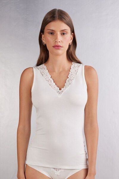 Soft modal tank top with neckline trimmed with an elegant floral motif lace ruffle. V-neck Tank Top With Lace Trim For Daywear, Elegant V-neck Tank Top With Lace Trim, Feminine Lace Tank Top, Elegant V-neck Tops With Lace Trim, Feminine Lace Trim Tank Top, Elegant Seamless Tank Top For Summer, White Feminine Tank Top With Delicate Lace, Feminine White Lace Tank Top, Elegant Summer Tops With Delicate Lace