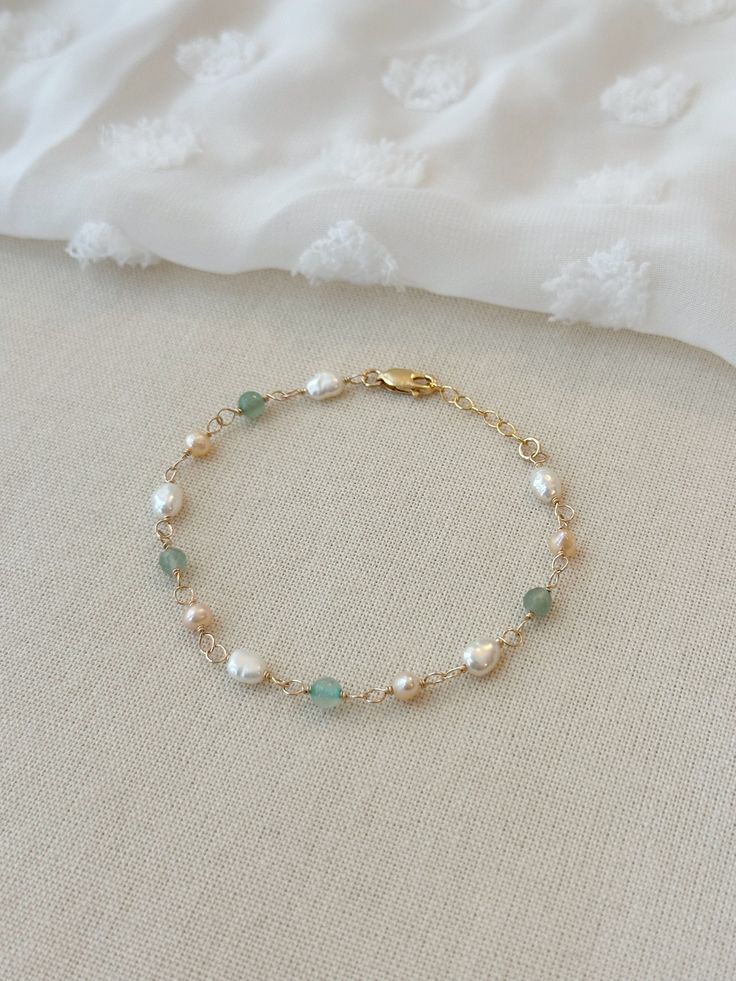 Please review the bracelet sizing guide below for the perfect fit! BALBOA PEARL BRACELET This pastel mixed Pearl and gem bracelet makes a beautiful addition to any bracelet stack! Each bead is hand wrapped in 14K Gold Filled or 925 Sterling Silver. The natural Aventurine gemstones are a mix of smooth and sparkly stones. * 4 mm natural Green Aventurine * 5-7 mm pink and white Pearls * 14K Gold Filled or 925 Sterling Silver accents * 14/20 GF for authenticity * Adjustable fit: 6.75" with 1" extend Emerald And Pearl Bracelet, Good Bracelets For Women, Beaded Bracelets Silver, Cute Homemade Bracelets, Wire Bracelet Ideas, Gem Bracelets, Diy Gold Jewelry, Simple Bead Bracelet, Wired Bracelet