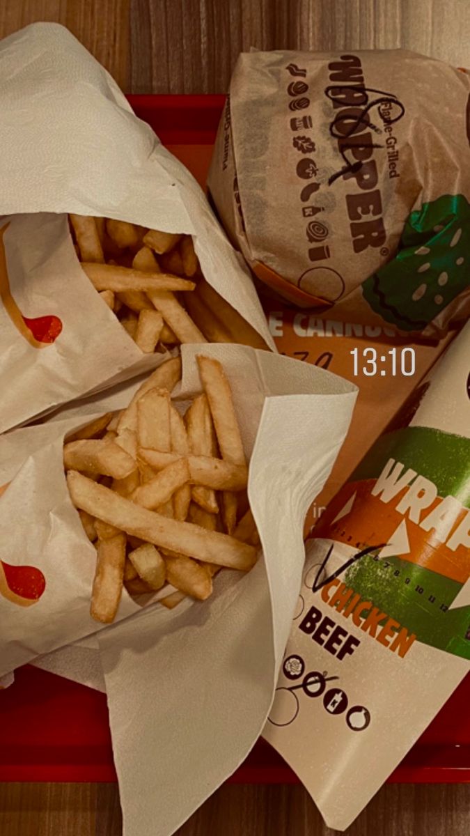 two bags of french fries sitting on top of a red tray next to each other