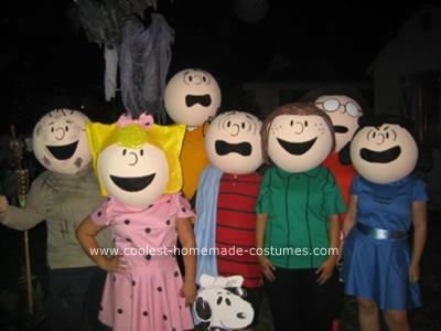 a group of people standing next to each other in front of some pumpkins with faces on them