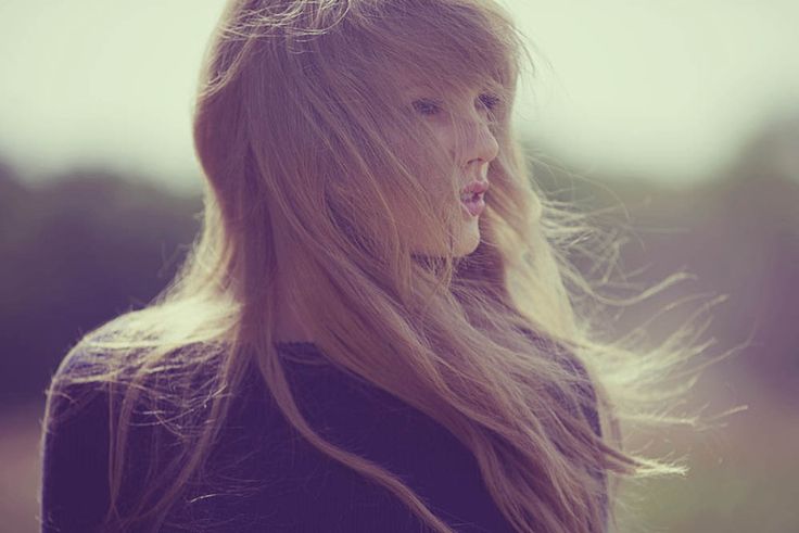 a woman with long blonde hair blowing in the wind and looking off into the distance